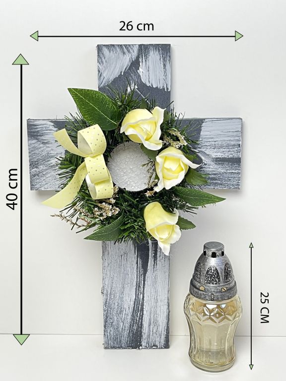 Kríž so sviečkou a umelým kvetom v krémovej farbe.