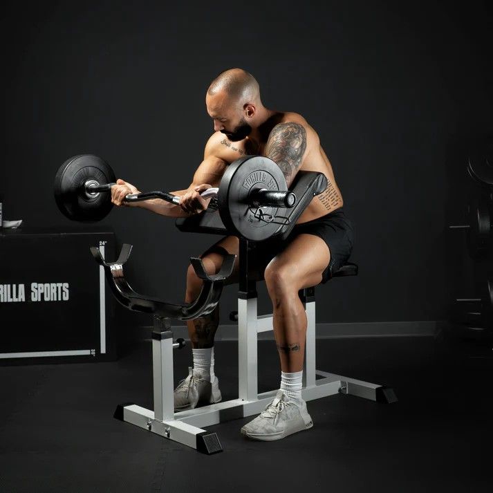 Muž cvičí biceps na nastavitelné bicepsové lavici se stojanem na činku