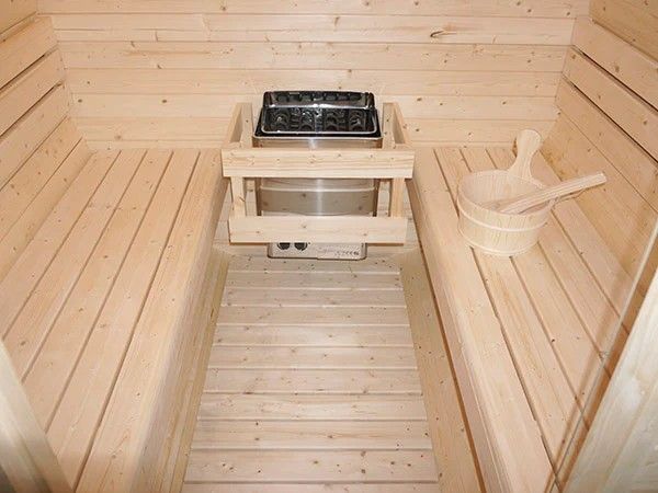 Detail saunových kamen s kameny na saunování obklopených dřevěným zábradlím